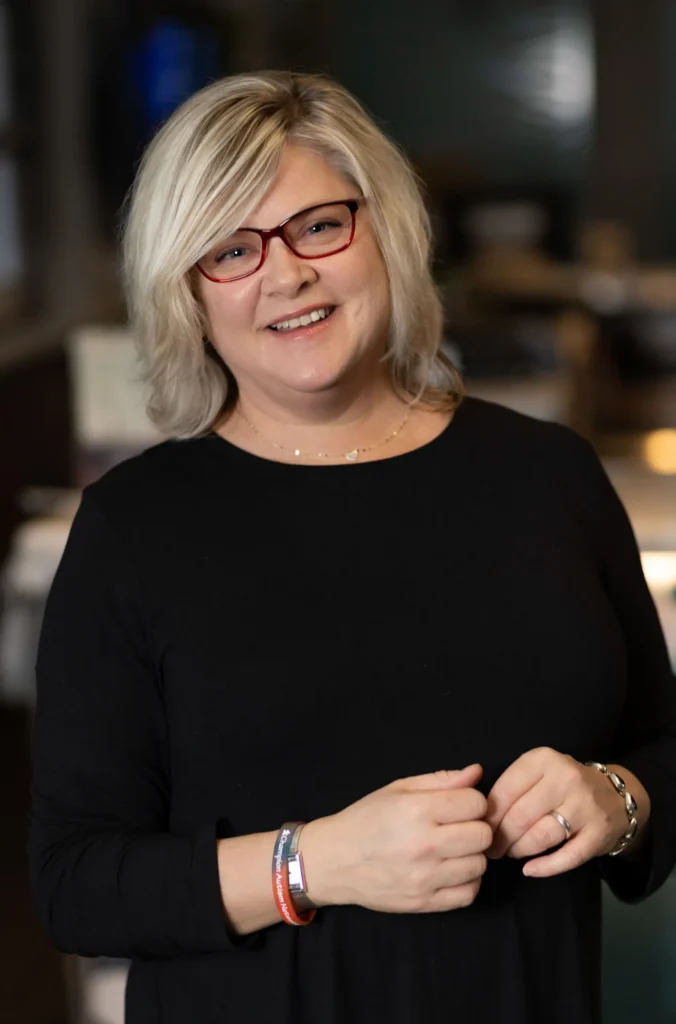 Headshot of a smiling blonde woman in a black top.