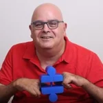 A smiling man in a bright red golf-shirt holds bright blue blocks between his hands. Headline reads, Yuval Wagner, Founder & Chairman of Access Israel.