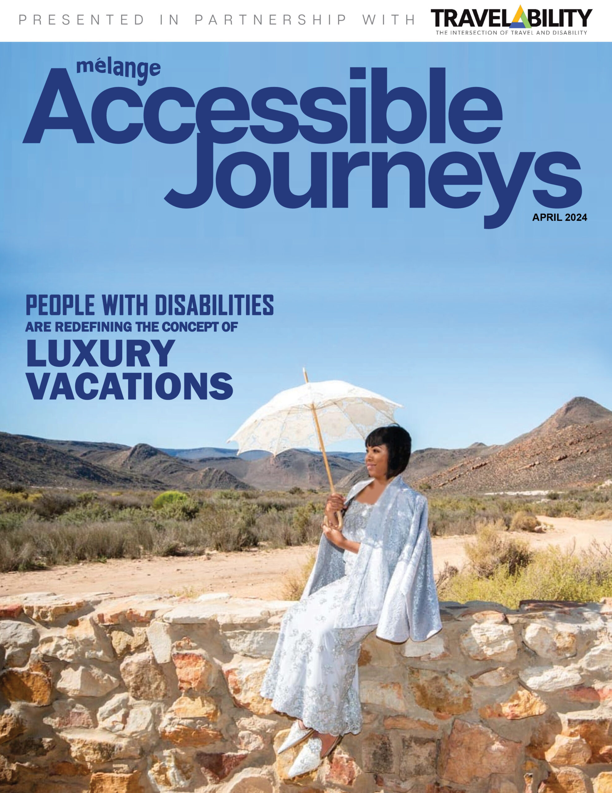 Alt text: "Cover of the April 2024 issue of 'mélange' Accessible Journeys magazine, presented in partnership with 'TRAVELability - The Intersection of Travel and Disability'. The cover features a smiling woman elegantly dressed in a flowing white lace gown with a matching parasol, seated on a stone wall in a desert landscape. The sky is clear and blue, and desert mountains can be seen in the background. The cover headline reads 'Accessible Journeys' and a tagline below states 'People with disabilities are redefining the concept of luxury vacations'