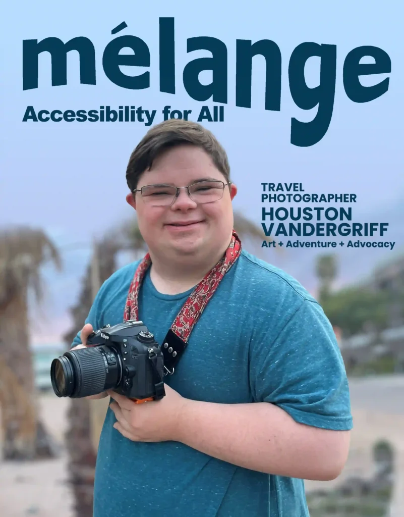 A magazine cover titled "mélange" with the tagline "Accessibility for All" features a travel photographer named Houston Vandergriff. He is smiling and holding a professional Nikon camera, with a camera strap around his neck. Houston, dressed in a blue t-shirt, stands outdoors with palm trees and mountains blurred in the background. The cover highlights his focus on art, adventure, and advocacy.