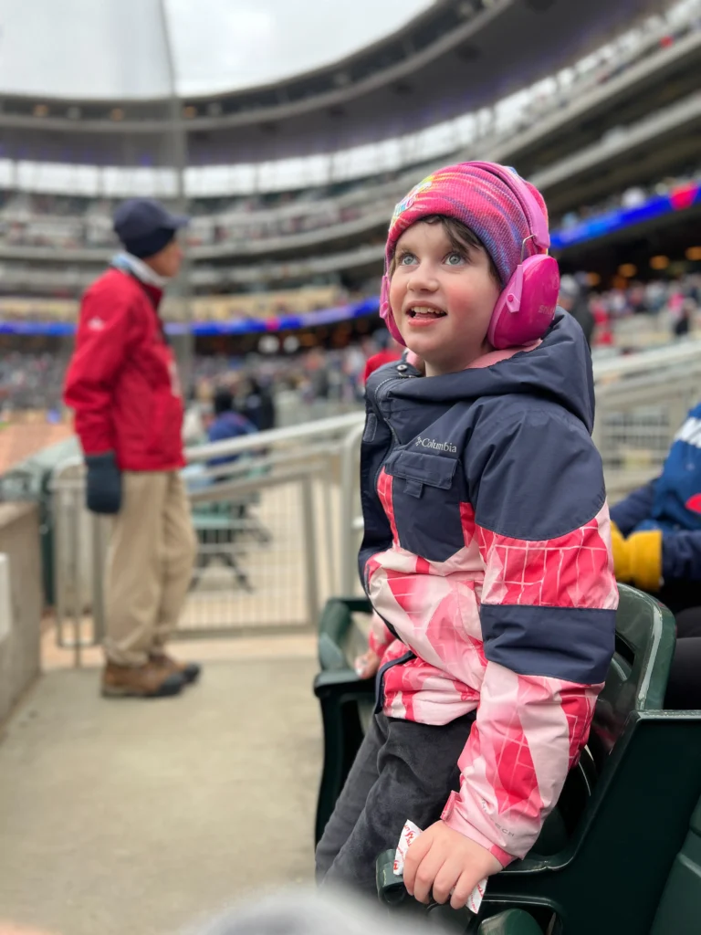 A woman and a child smiling while interacting with a character dressed as Minnie Mouse, who is wearing a pink dress. The setting appears to be an indoor event space with a whimsical design.