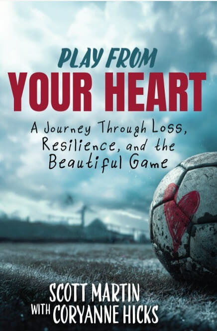 The book cover for "Play From Your Heart" by Scott Martin with Coryanne Hicks. The title is in large red and teal font against a dramatic, cloudy sky. Below the title, the subtitle reads, "A Journey Through Loss, Resilience, and the Beautiful Game." In the foreground, a weathered soccer ball sits on a grass field with a red heart hand-painted on its side.