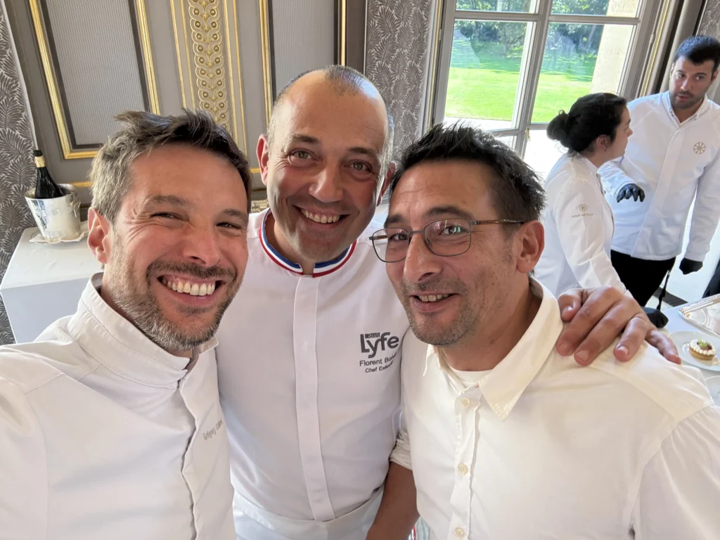Three chefs in white uniforms, including Grégory Cuilleron and Florent Boivin, smiling for a close-up selfie at the Institut Lyfe.