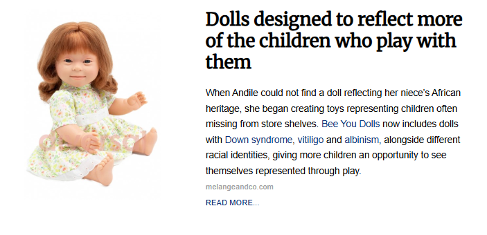 A baby doll with Down syndrome features, red hair, and a floral print dress sitting against a white background.